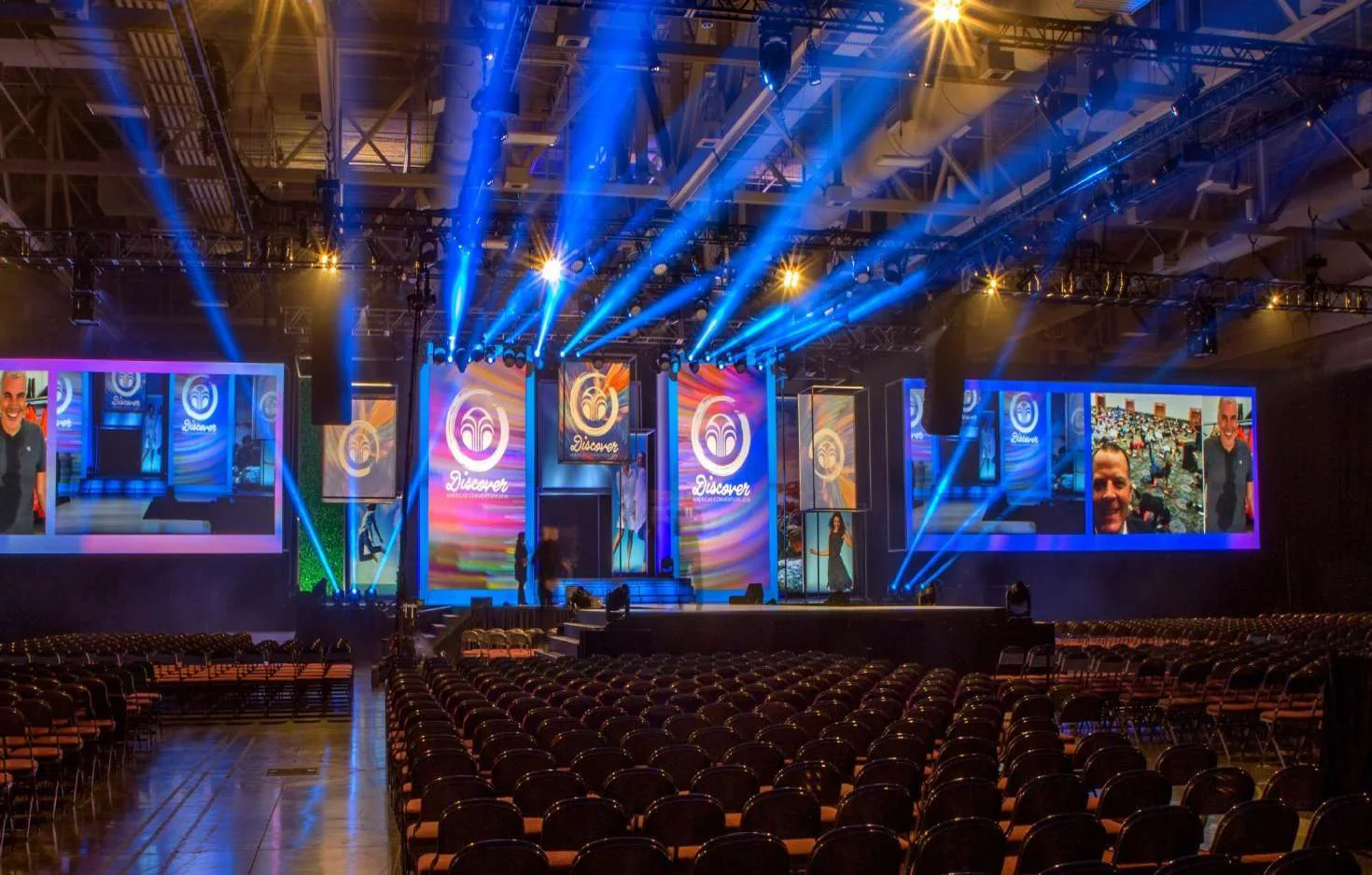 Conference stage with large screens and blue event lighting